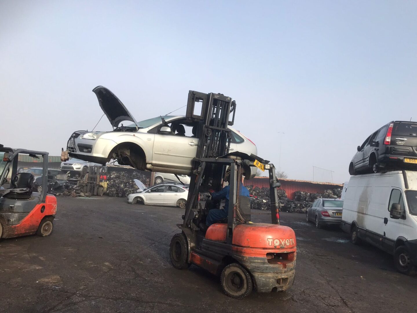 A forklift is lifting a car in the air.