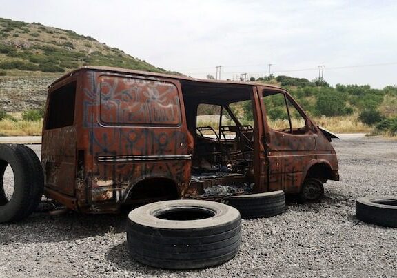 A van that has been burnt out and sitting on the ground.