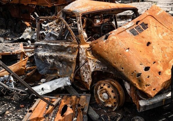 A burnt out car in the middle of rubble.